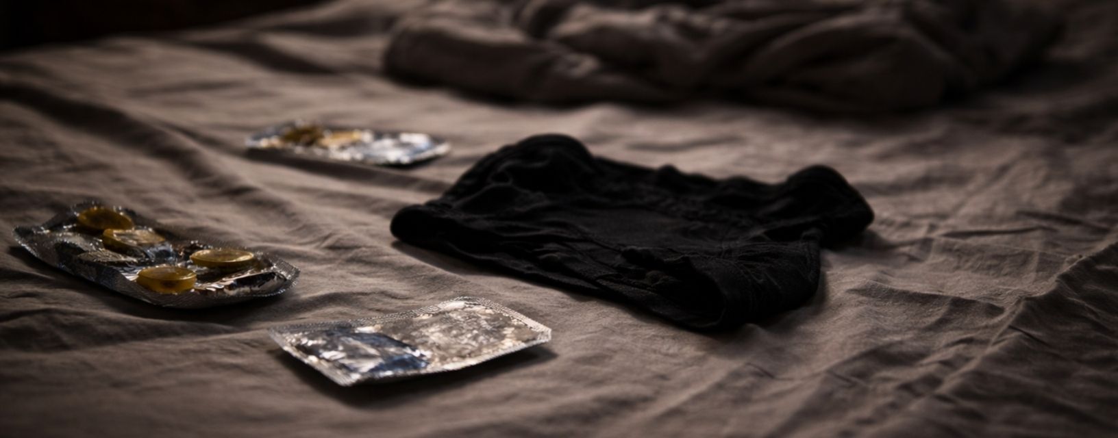 Preservativos sobre uma cama representando prevenção e proteção contra o VIH durante relações sexuais