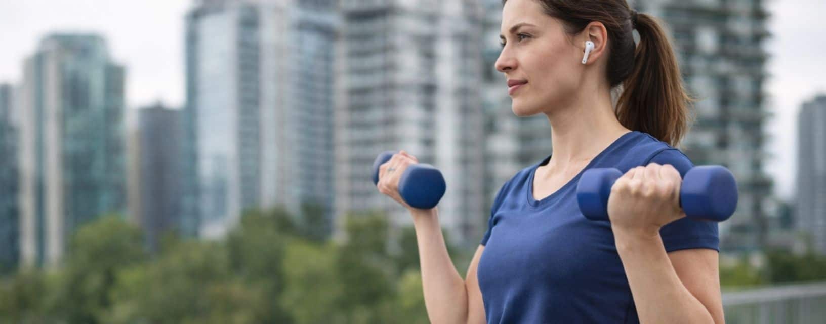 Mulher a praticar exercício com halteres ao ar livre durante tratamento médico